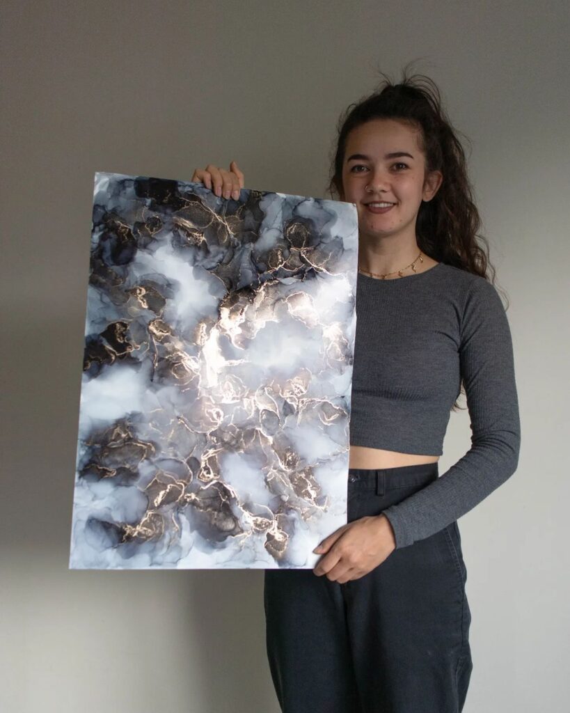 Coya holding an alcohol ink painting